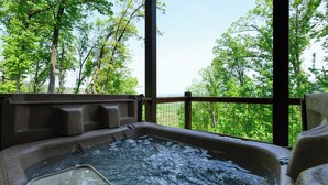 A hot tub with a view of a forested area. - Mountain Magic: The Perfect Romantic Cabin Getaway (Gatlinburg)