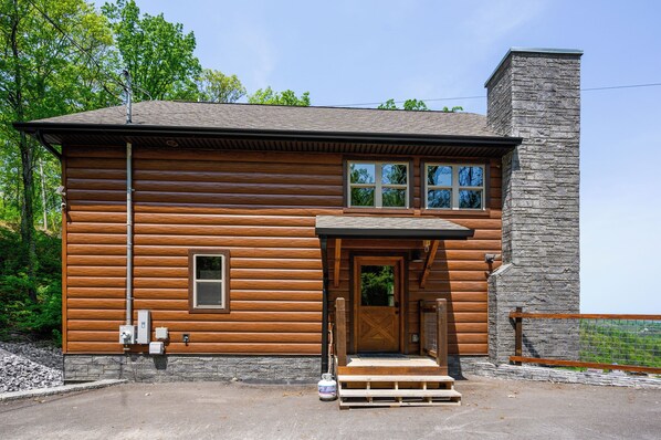 A log cabin with a stone chimney, a wooden door, and a small window.