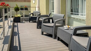 Un patio al aire libre con mobiliario de mimbre y plantas en macetas.