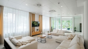 Una sala de estar moderna con un conjunto de sofá, dos mesas auxiliares y un televisor de pantalla plana.