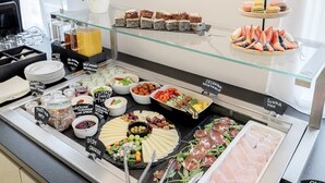 Un bufé con una variedad de alimentos, como queso, carnes y pasteles.
