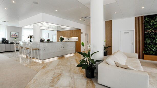 Amplia sala de estar con una cocina moderna, un sofá blanco grande y un comedor con sillas.