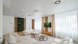 Una sala moderna con un conjunto de sofá, una mesa de centro y un televisor de pantalla plana montado en la pared.