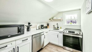 A compact kitchen with a microwave, coffee maker, toaster, sink, dishwasher, and oven. - Charming & Bright Gem: Awesome Location/AC/Laundry (Renton)