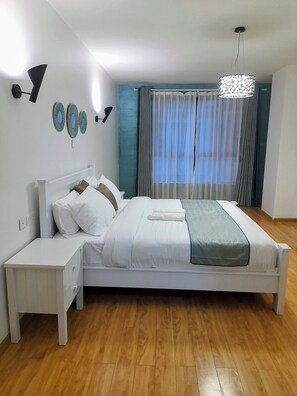 Relax in a serene bedroom with a neatly made bed, bedside table, and wall-mounted light fixture.