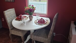 A dining table with wicker chairs, a vase of flowers, and a red and white checkered napkin.