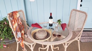 A wicker table set with a wine bottle, glasses, a hat, and sunglasses.