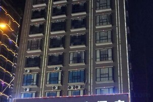 Un edificio de varios pisos con unidades de aire acondicionado en la fachada, varias ventanas y un techo plano.