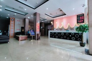 A hotel reception area with a reception desk, a digital display, and a seating area. - Fuyang Youyou Express Hotel (High-speed Railway Station) (Shaoyang)