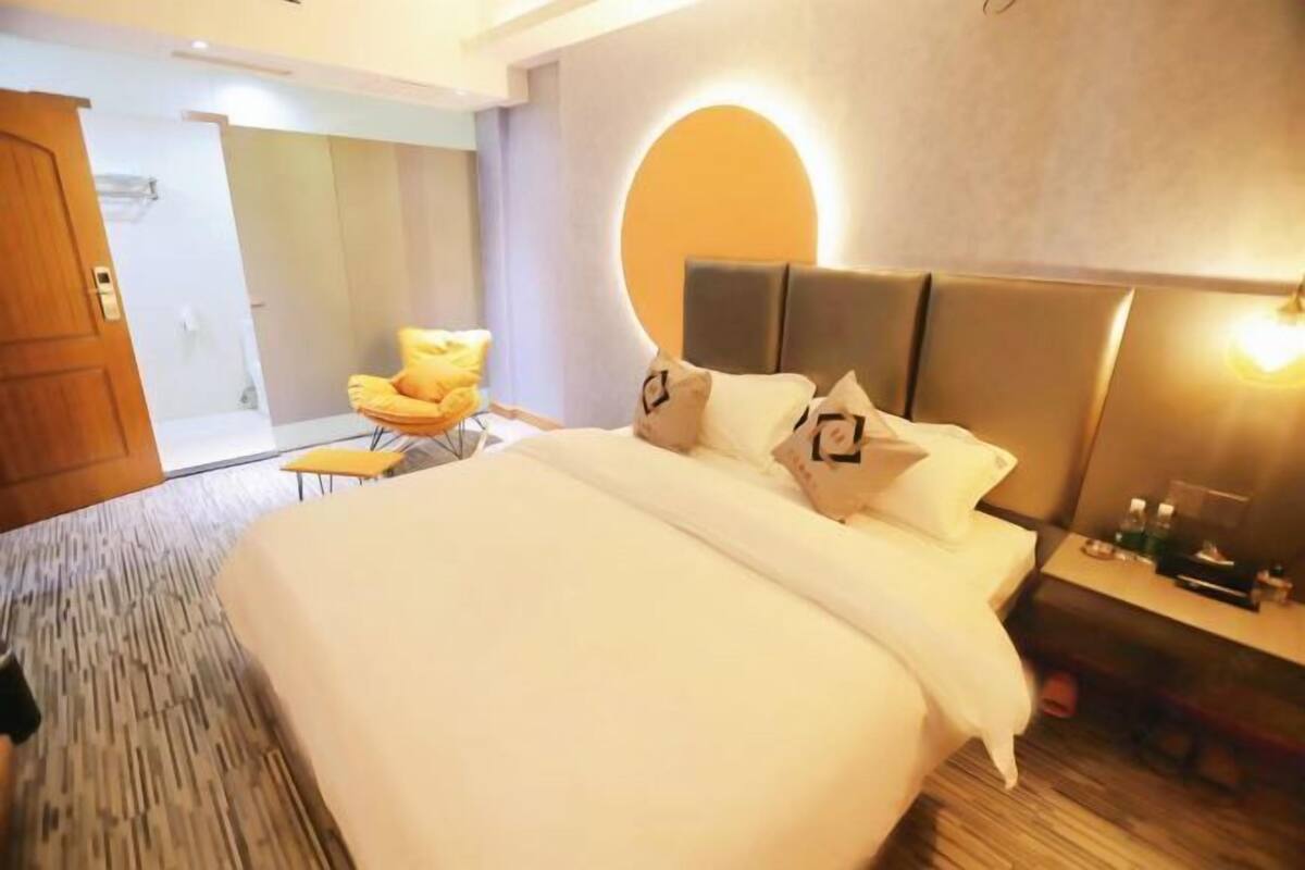 Ein Hotelzimmer mit einem großen Bett, einer runden Wandleuchte, einem kleinen Tisch und einem Sessel.