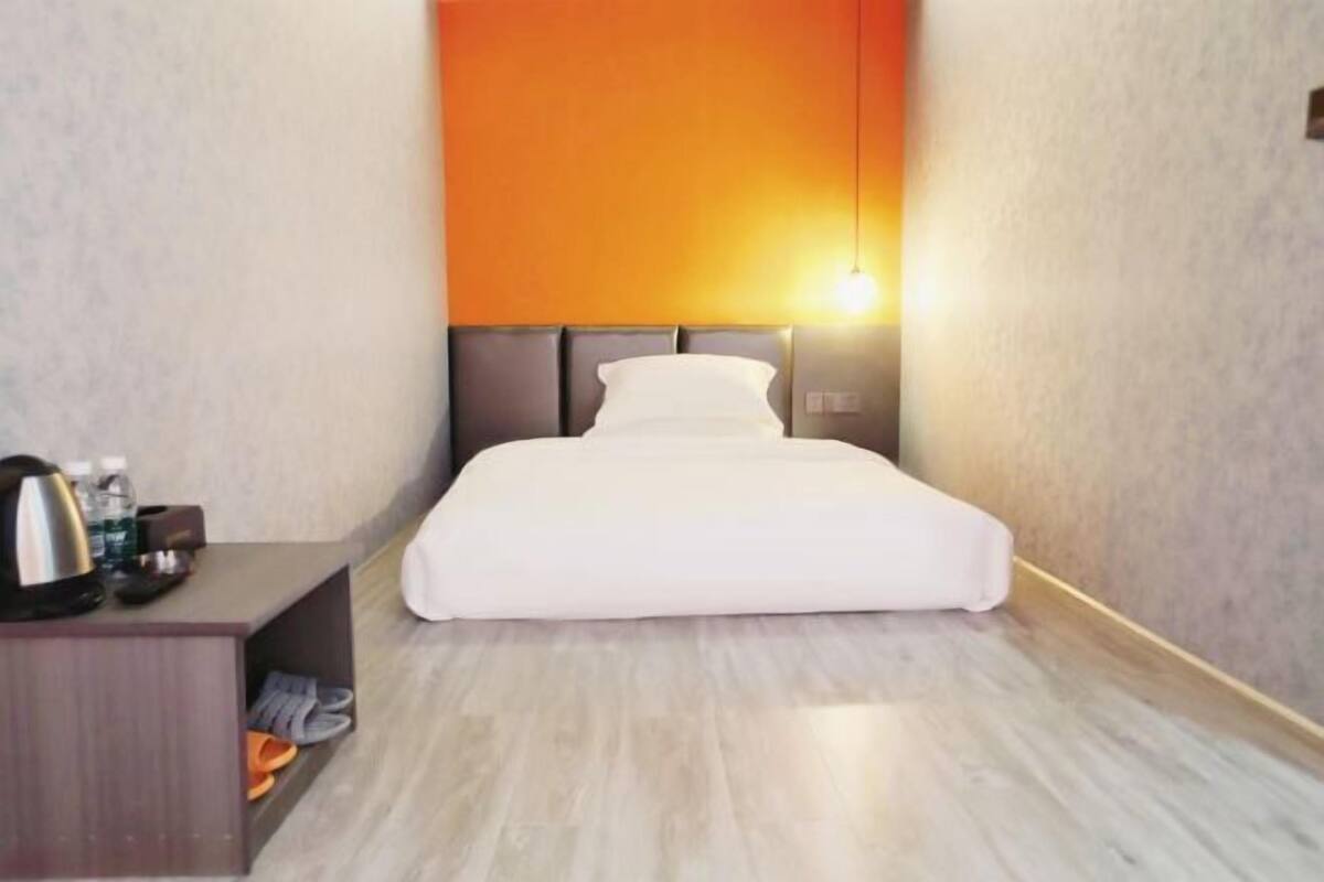 Ein Hotelzimmer mit Bett, Nachttisch und Wandlampe.