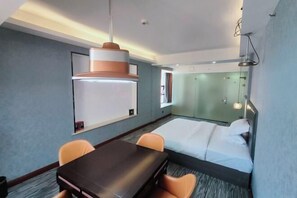 A hotel room with a bed, a desk, two chairs, a large pendant light, a whiteboard, and a glass partition. - Fuyang Youyou Express Hotel (High-speed Railway Station) (Shaoyang)