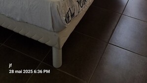 Una camera da letto con un letto, una finestra con tende e vista su uno spazio esterno con tavolo e sedie.