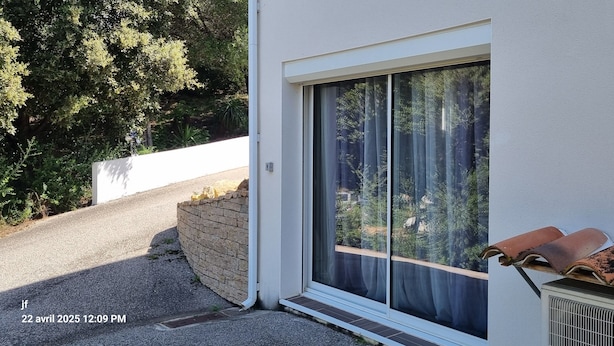 Un edificio con un'ampia porta scorrevole in vetro, un muro in mattoni e un condizionatore d'aria metallico.