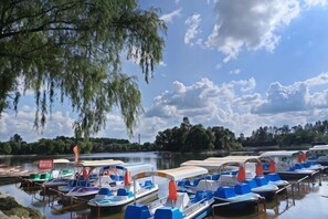A marina with boats docked, calm water, and trees in the background.