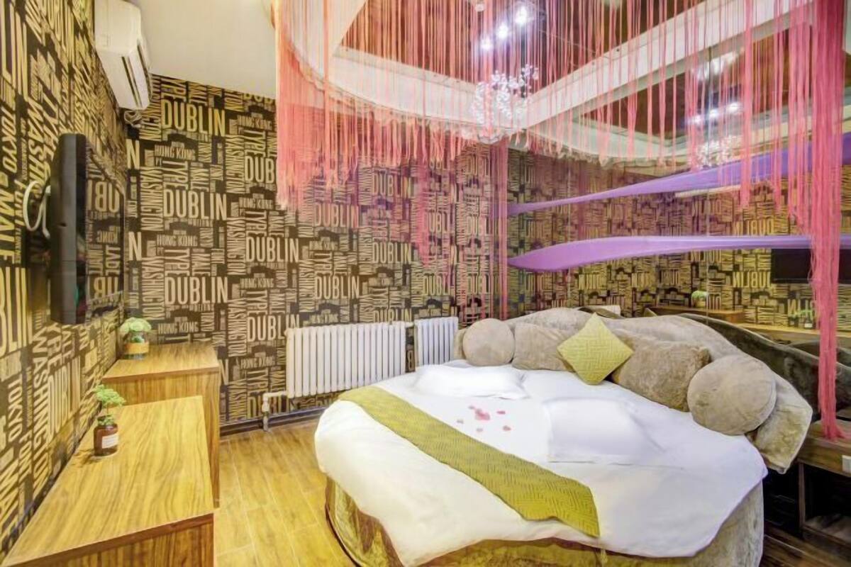 A hotel room with a bed, a desk, and a radiator.