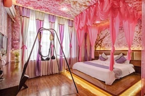 A bedroom with a canopy bed, a swing chair, and a wooden floor. - Harbin Xinxulong Business Hotel (Government Grand Plaza) (Harbin)