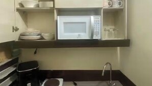 A compact kitchenette with a microwave, sink, and storage cabinets. - Cozy, secure and private suite  (Guayaquil)
