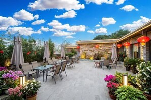 An outdoor patio with tables and chairs, surrounded by potted plants and red lanterns. - Boerman Hotel (Chengdu Conference and Exhibition Center) (Chengdu)