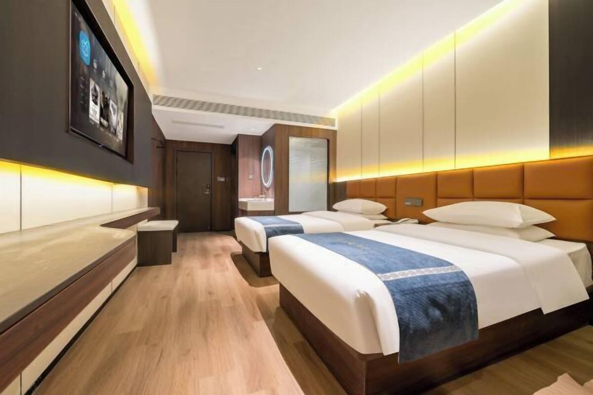 A hotel room with two beds, a seating area, and a large mirror.