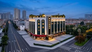 A modern hotel with a prominent entrance, large windows, and a rooftop garden.