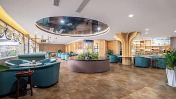 Um hall amplo com área de estar central, detalhe circular no teto e espaço de bar com vista para a cidade.