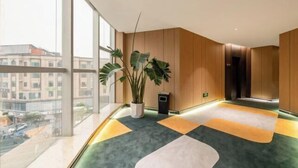 A modern interior with large windows, a potted plant, and a geometric carpet design.