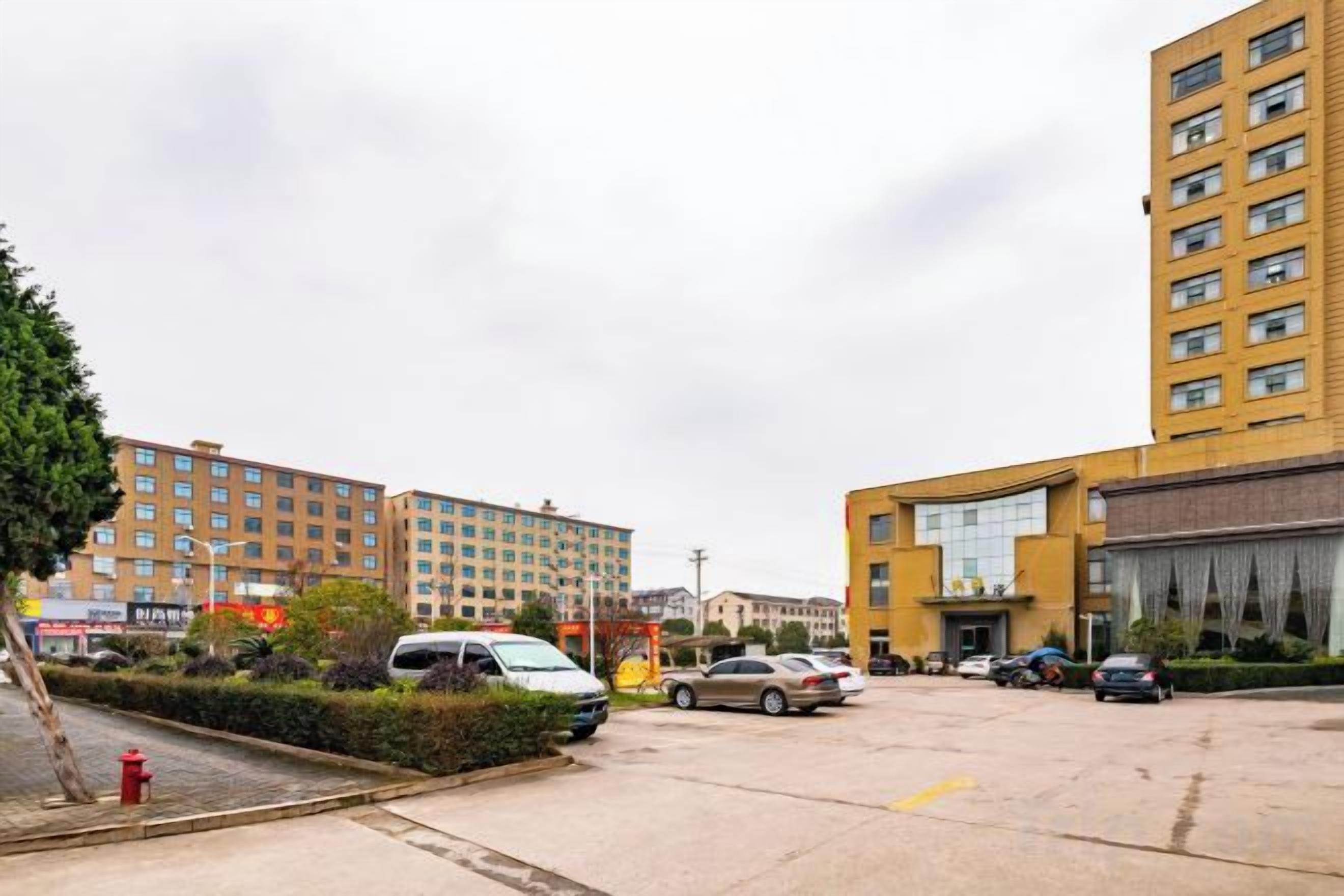 Un parking avec plusieurs voitures, un hydrant rouge et des bâtiments en arrière-plan.