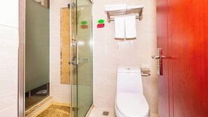 Un baño con cabina de ducha de vidrio, un inodoro blanco y una puerta roja.