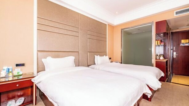 Habitación de hotel con dos camas, una mesita de noche de madera, un espejo y un armario.