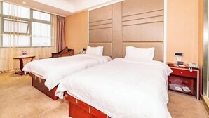 Una habitación de hotel con dos camas, cabecero de madera, mesita de noche y ventana con cortinas.