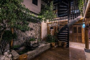 A courtyard with a stone wall, wooden deck, and a staircase leading to a traditional door. - Tinglan Xiaoju Inn (Dali City)