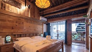 Quarto estilo cabana de madeira, com cama, mesas de cabeceira, abajur e vista para o exterior.