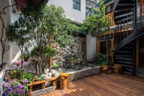 A wooden deck with a stone wall, potted plants, and a staircase. - Tinglan Xiaoju Inn (Dali City)