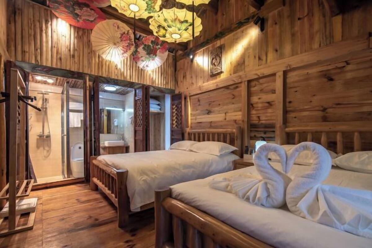 A wooden room with two beds, a wooden ceiling, and a traditional fan.