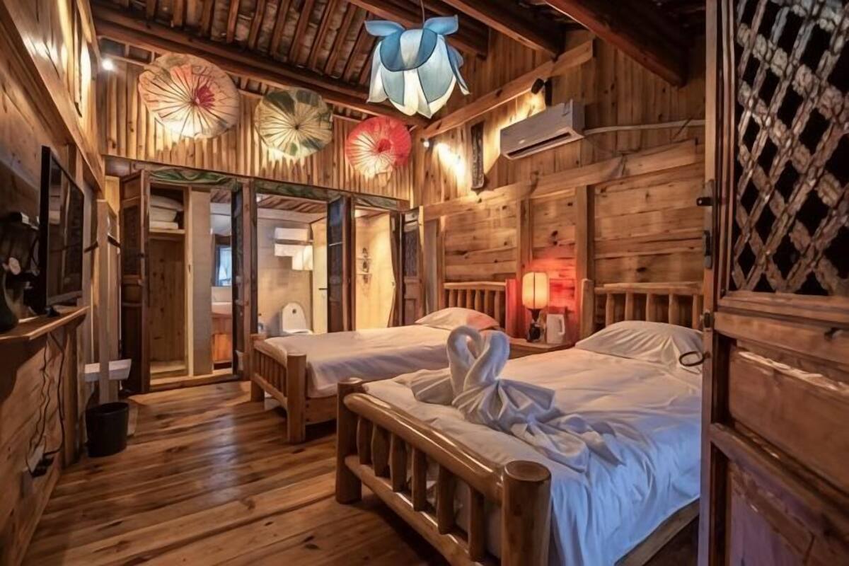 A wooden cabin-style room with two beds, a ceiling fan, and a wooden lattice wall.