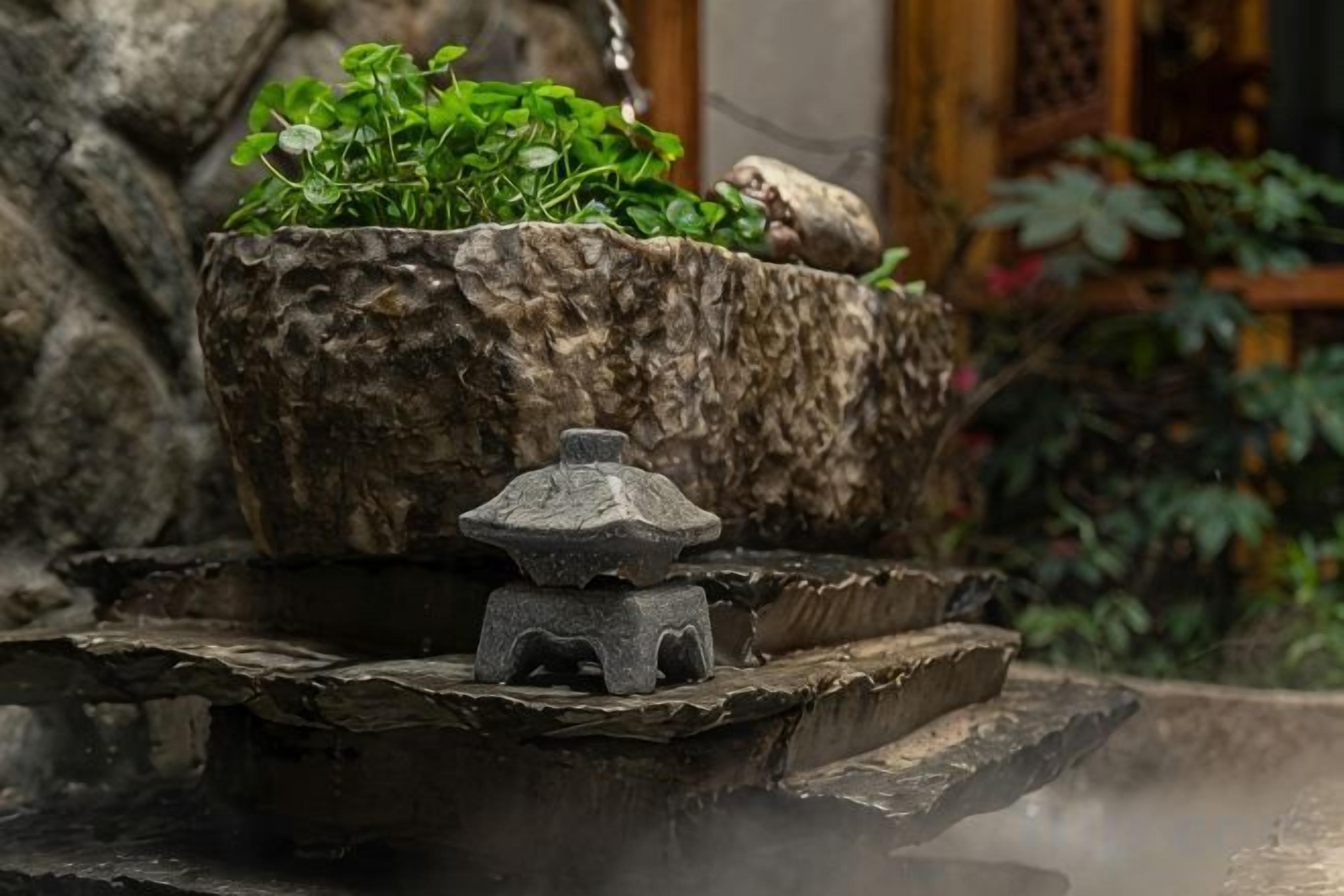 A stone lantern on a tiered platform with a potted plant.