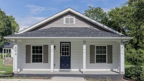 A single-story house with a dark blue front door, white siding, and a small porch with two windows. - Charming 2-bedroom house with AC and WiFi in enjoyable China Grove (China Grove)