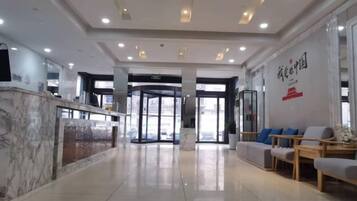 A hotel lobby with a reception desk, seating area, and a revolving door.