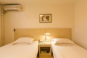 A hotel room with two beds, a nightstand with a lamp, a framed picture on the wall, and an air conditioning unit. - Jinjiang Inn (Xi'an Jianguomen, Jiaotong University, Hepingmen Metro Station) (Xi'an)
