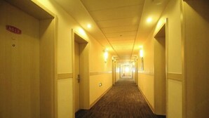 En hotellkorridor med mattbeklädd golv och dörrar på båda sidor.