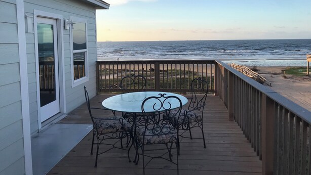 A wooden deck with a glass table and chairs, overlooking a beach and ocean. - 3-bedroom house in charming Surfside Beach with AC, WiFi (Surfside Beach)