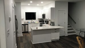 A modern kitchen with white cabinetry, a central island, and a dark wood floor. - 3-bedroom house in charming Surfside Beach with AC, WiFi (Surfside Beach)