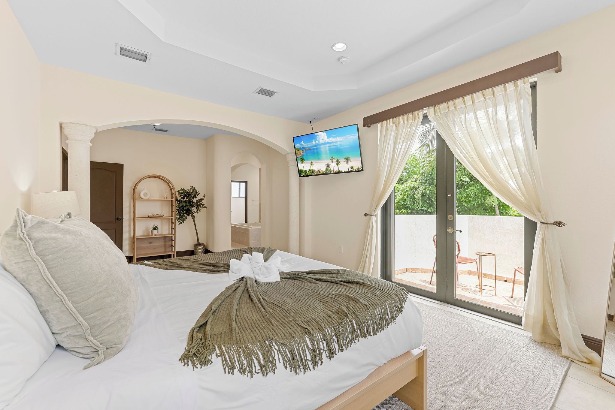 Una camera da letto con un letto, una TV e un balcone con tende.