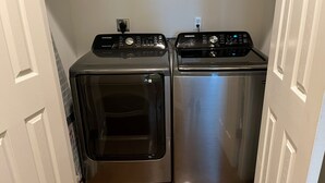 Une buanderie équipée de deux lave-linge et deux sèche-linge à chargement frontal en acier inoxydable.