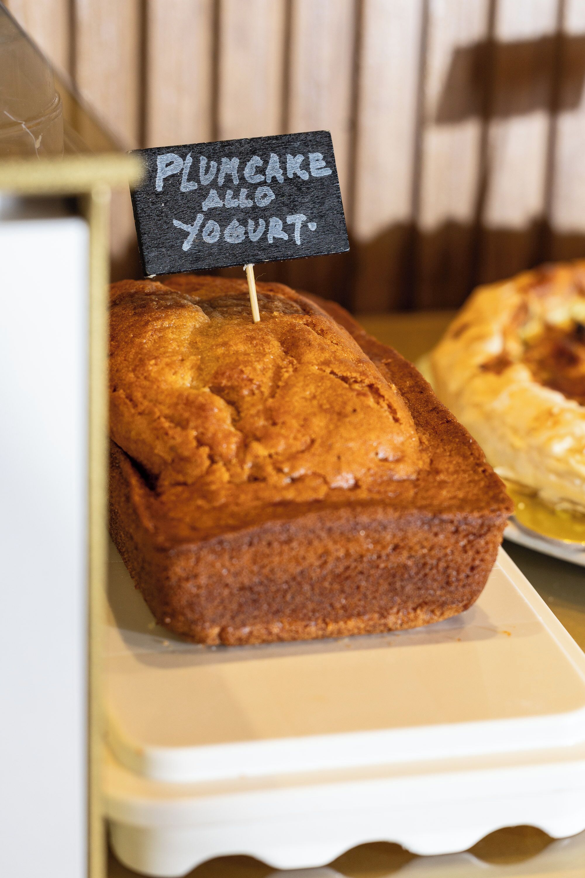 Un pain aux fruits confits, accompagné d’une étiquette indiquant qu’il est servi avec du yaourt.
