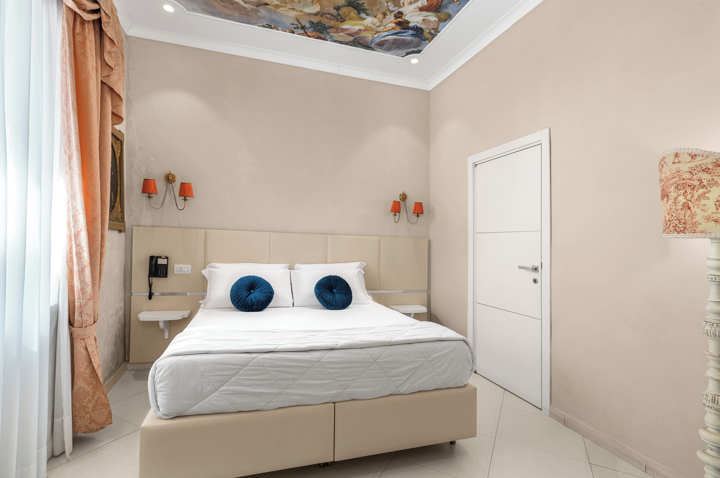Un dormitorio con una cama, una mesita de noche, un teléfono y una puerta.