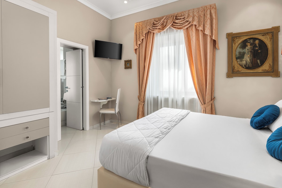 Une chambre à coucher avec un lit, un bureau, une chaise, un téléviseur et un tableau accroché au mur.