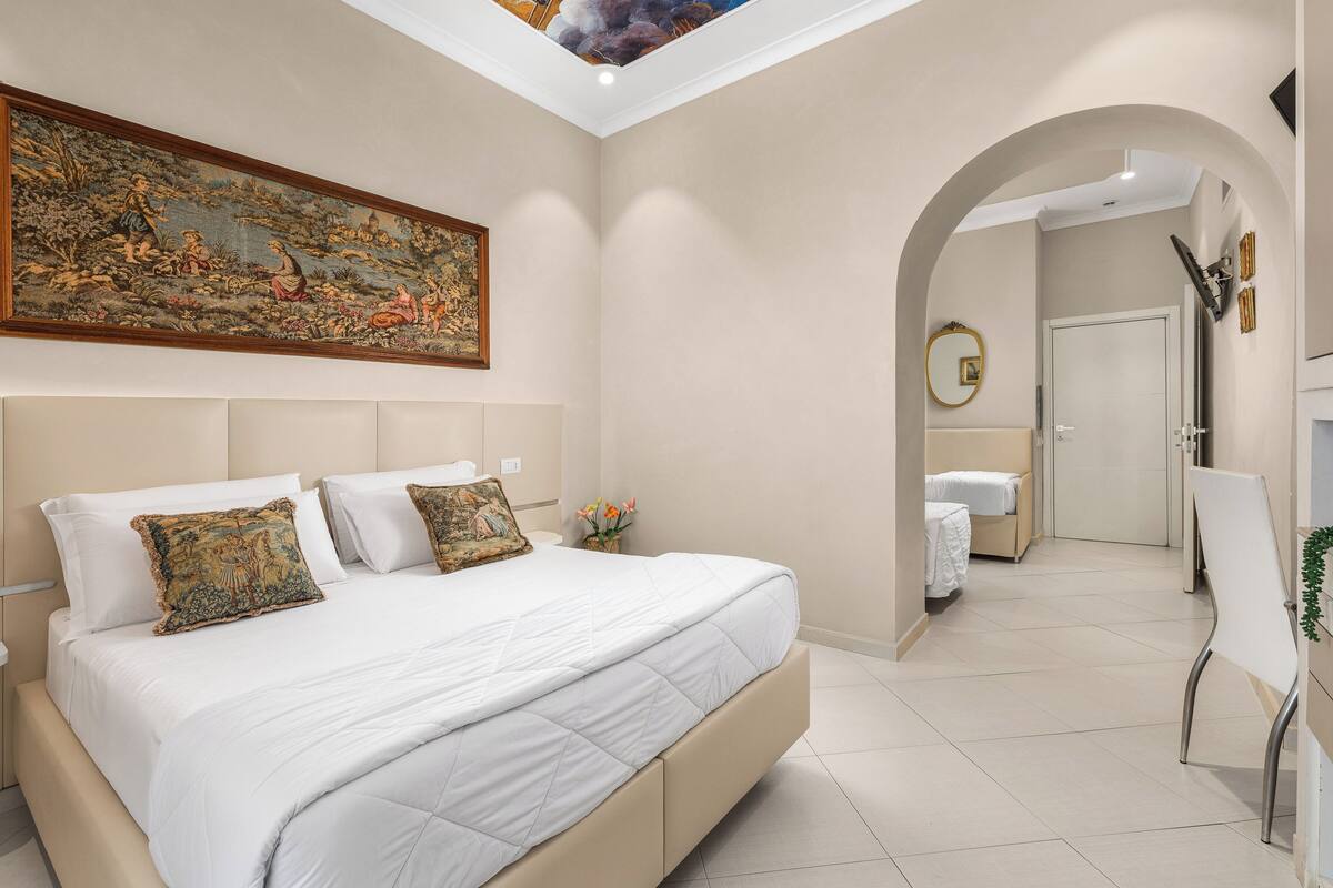 Une chambre avec un grand lit, un tableau au mur et une lucarne.