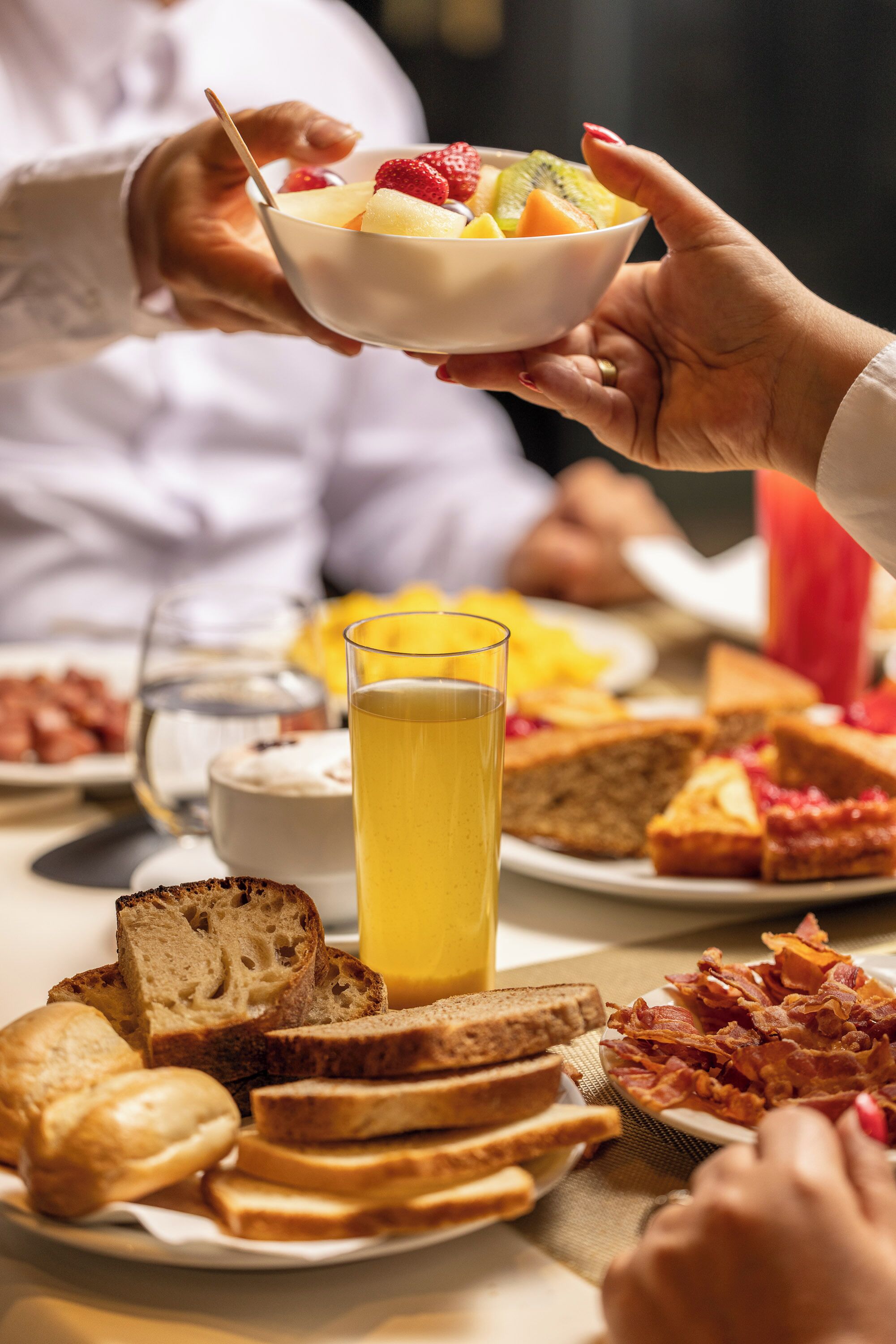 Un desayuno con tostadas, tocino y un bol de fruta.